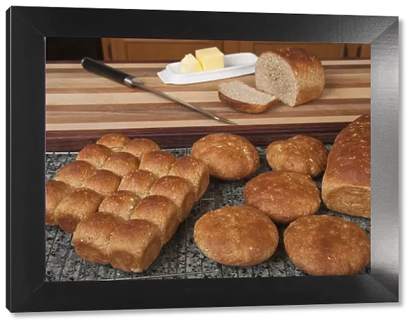 Multigrain rolls, buns and loaf with a slice cut off, with butter and a bread knife