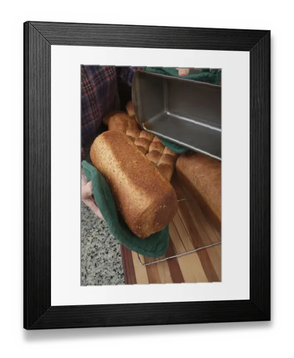 Framed Print : Woman removing loaf of just baked multigrain bread from bread pan. (MR) Framed Print : Woman removing loaf of just baked multigrain bread from bread pan. (MR)