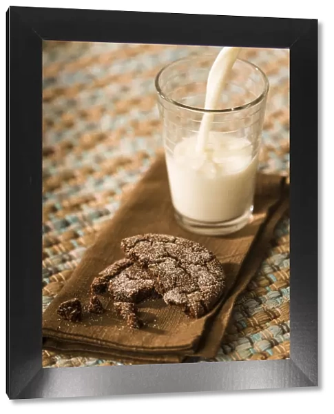 Snack of a homemade chocolate sugar cookie, with milk being poured into a glass