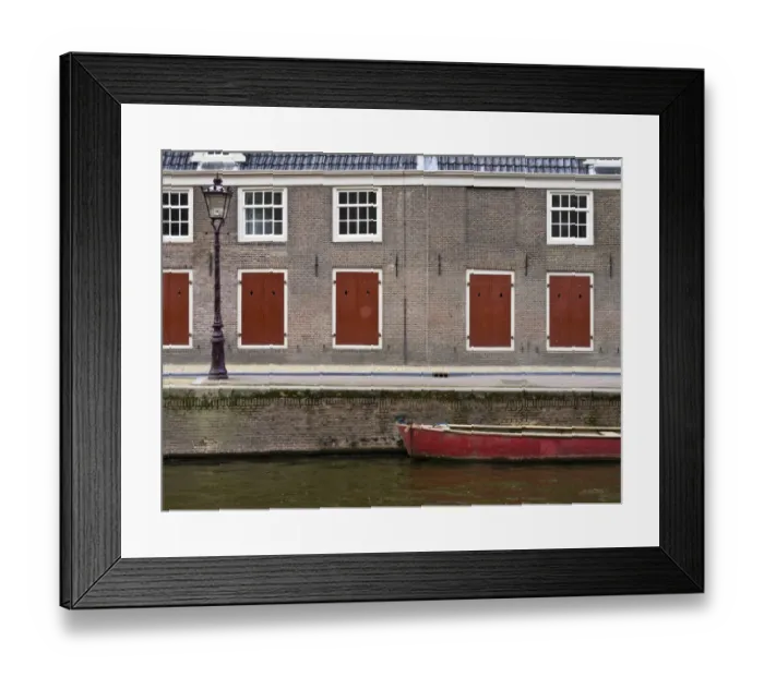 Framed Print : Netherlands, Amsterdam. Colorful red doors along the canal with a red boat