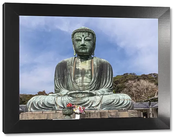 The Great Buddha, Daibutsu, offerings in front, blue sky above in Kamakura, Japan