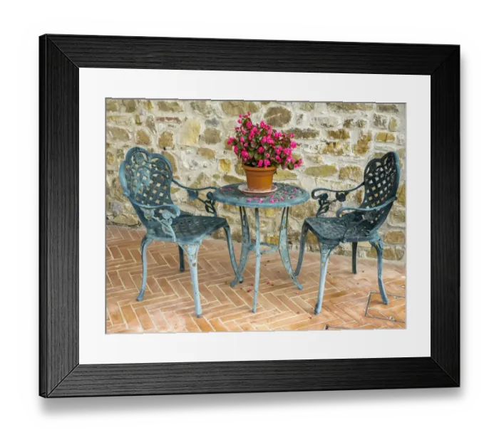 Framed Print : Europe, Italy, Chianti. Table and chairs with a flowering begonia in the center against a Framed Print : Europe, Italy, Chianti. Table and chairs with a flowering begonia in the center against a