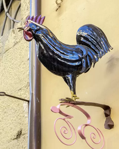 Europe, Italy, Chianti. Rooster with glasses above a shop in Radda in Chianti
