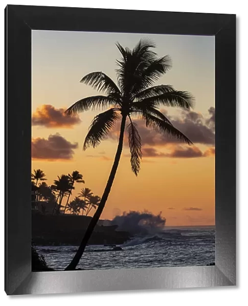 Coconut palm trees silhouetted against vivid sunrise clouds at Poipu Beach in Kauai