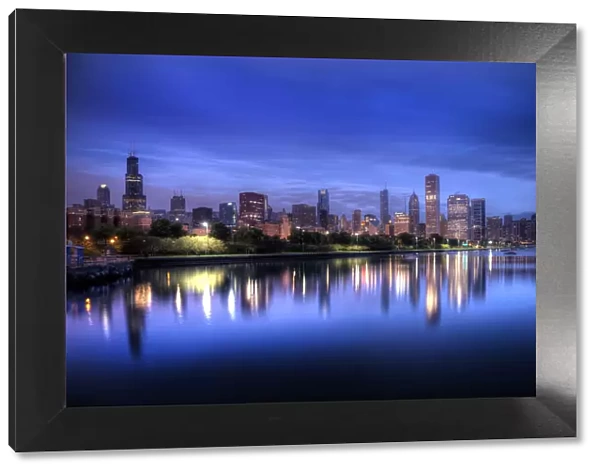 Chicago skyline reflects in lake Michigan during a blue sunrise