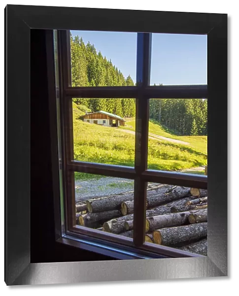 View out a window toward a cabin nestled in the hills of the Austrian Alps