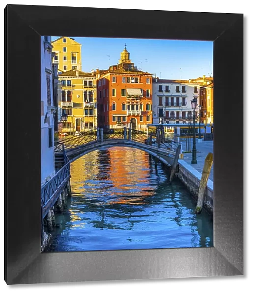 Colorful small canal and bridge Grand Canal creating beautiful reflection in Venice