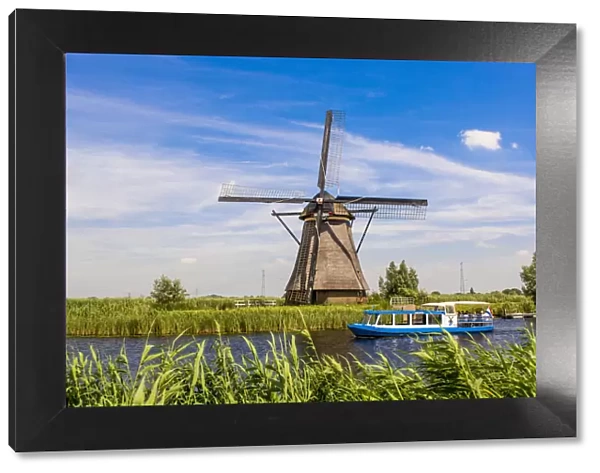 Canal tour boat and windmill in Unesco World Heritage Site, Kinderdijk, Holland