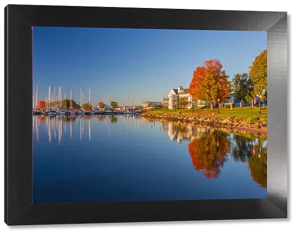 USA, Wisconsin. Fall colors reflected on the still waters of the harbor in Bayfield