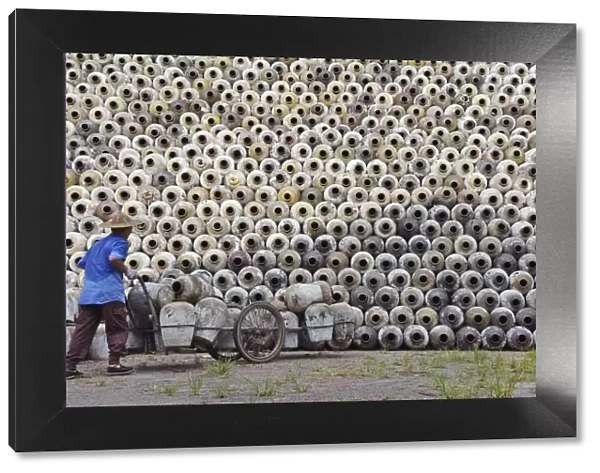 Man pushing cart loaded with wine jars to the big pile in a winery, Zhejiang Province