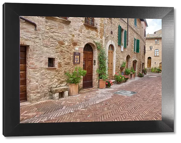 Italy, Tuscany, Pienza. Flower pots and potted plants decorate a narrow street in a Tuscany village