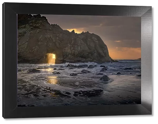 Usa, California. Sunsets gleams through this hole in the rock along the Big Sur coast