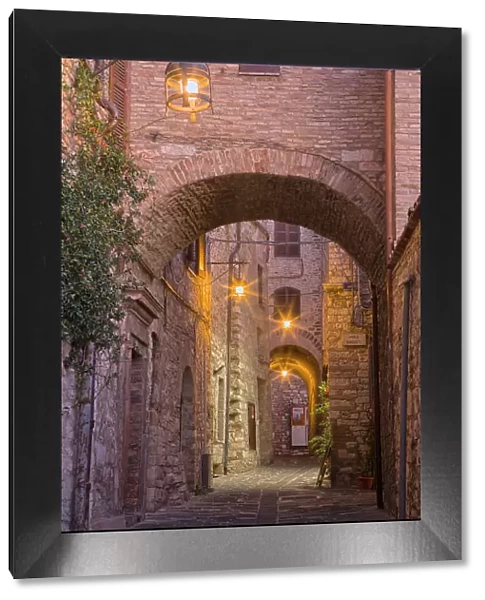 Italy, Umbria, Assisi. Alleyway with arches and lanterns in the evening