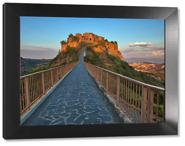 Italy, Tuscany. Evening light of Civita di Bagnoregio and the long bridge leading to town