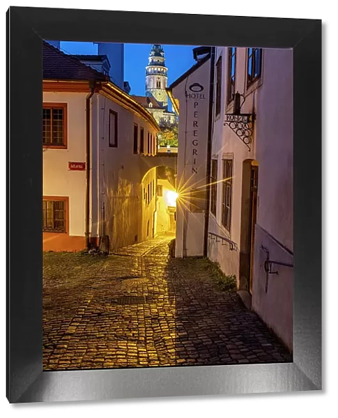 Narrow cobblestone streets at dusk with Castle Tower in historic Cesky Krumlov, Czech Republic. (Editorial Use Only)