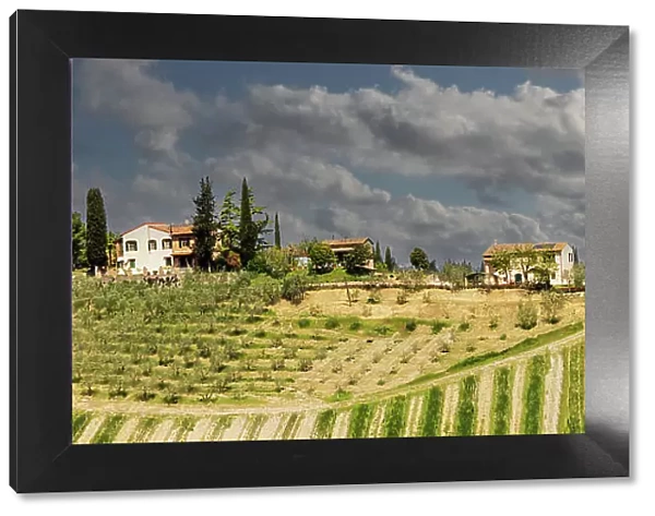 Tuscan landscape under thunder clouds. Farmhouse with vineyard. Tuscany, Italy