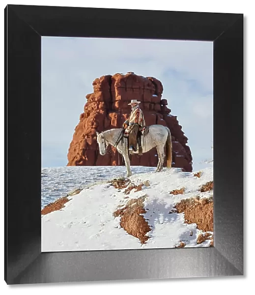 USA, Wyoming. Hideout Ranch cowgirl on horseback riding on ridgeline snow. (PR, MR)