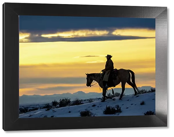USA, Shell, Wyoming. Hideout Ranch cowgirl silhouetted on horseback at sunset. (PR, MR)