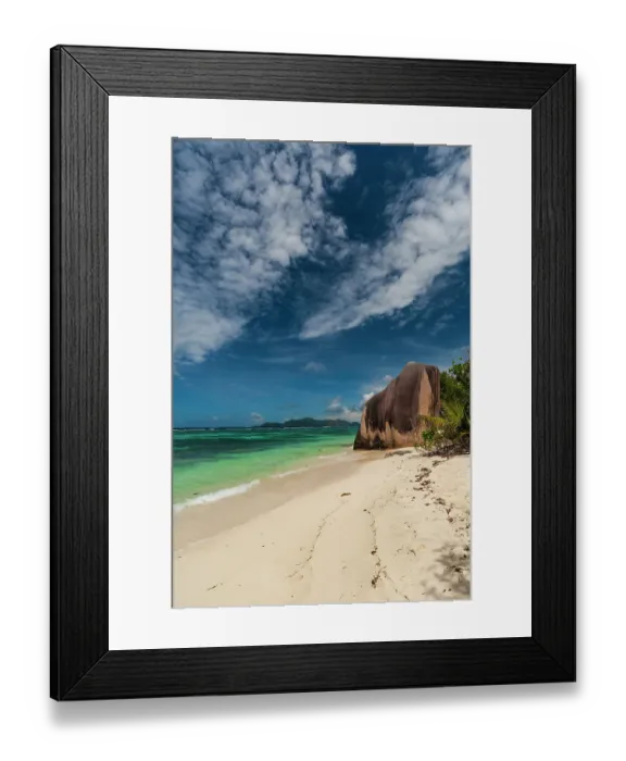 Framed Print : Wispy clouds over a sandy tropical beach with a large stone rock formation. Anse Source d Argent Beach, La Digue Island, Seychelles