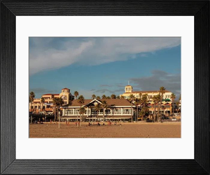 Framed Print : Volleyball players on Huntington Beach fronting sunlit waterfront buildings. Huntington Beach, California, USA. (Editorial Use Only)
