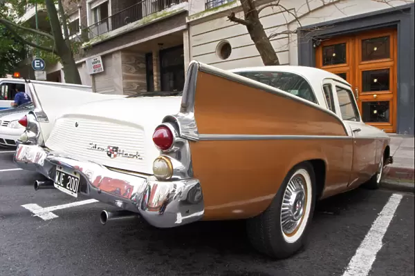 A Studebaker Silver Hawk Classic Car parked on a street, painted in cream white and brown