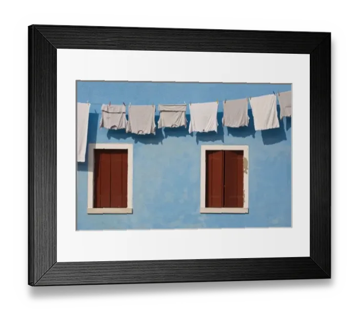Framed Print : Italy, Burano. Hanging laundry and windows along blue wall