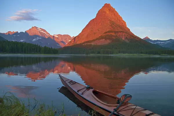 Wooden kayak in Swiftcurrent Lake at sunrise in the Many Glacier Valley of Glacier National Park