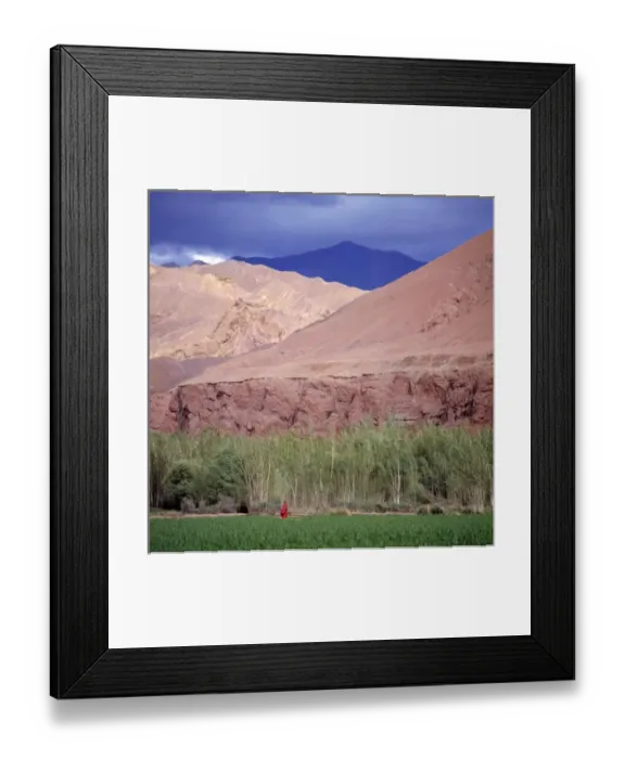 Framed Print : Afghanistan, Bamian Valley. A young girl waits in a field below pink cliffs in the Bamian Valley