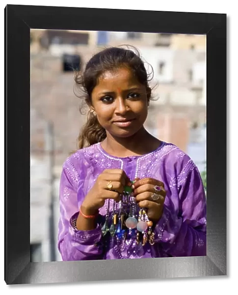Young Indian girl aged 15 in purple in front of village of Jodhpur in Rajasthan India