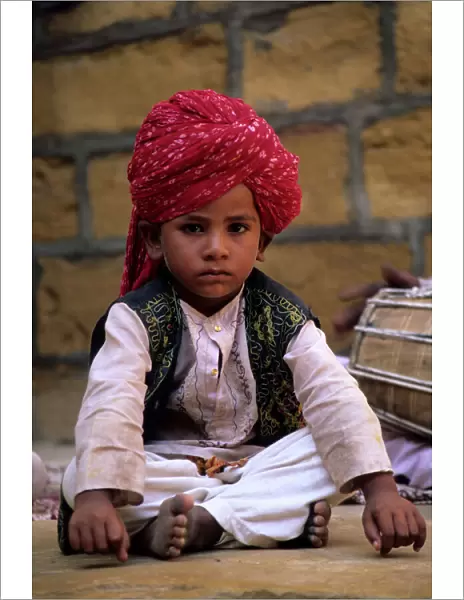 India, Rajasthan, Jaisalmer. Boy dancer rests between songs at entrance to Jaisalmer Fort