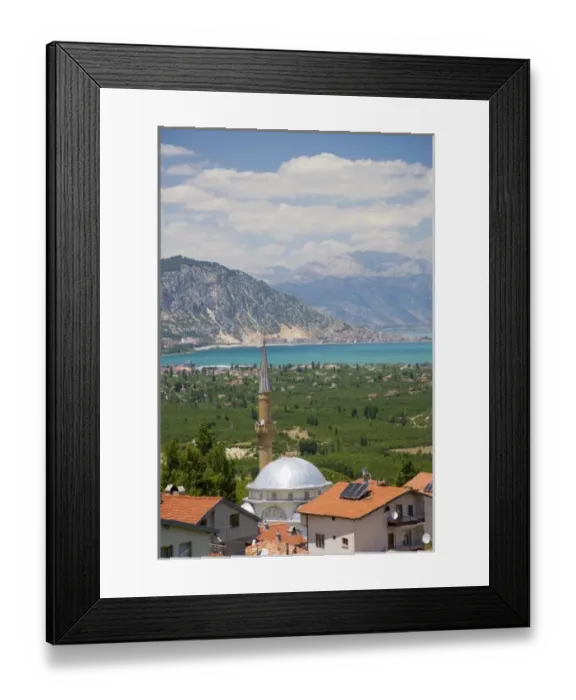 Framed Print : View of Lake Egirdir beyond hilly green land, village mosque with tin dome in front