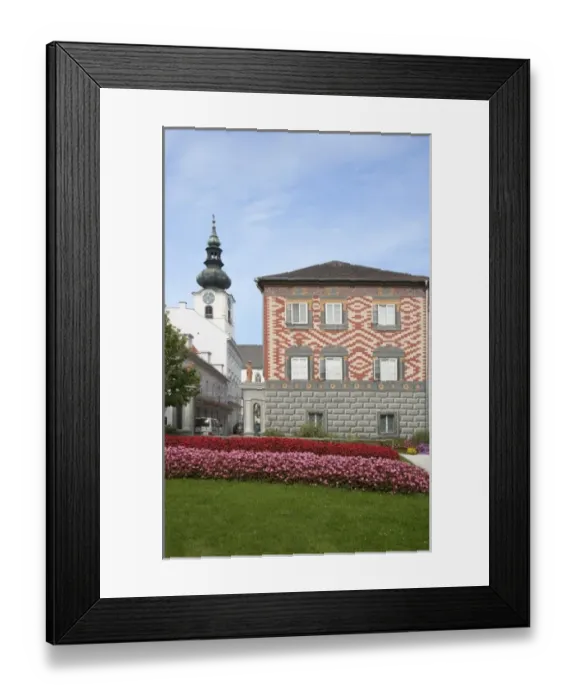 Framed Print : Wels, Upper Austria, Austria - Rows of red and pink flowers border a lawn in front of a building