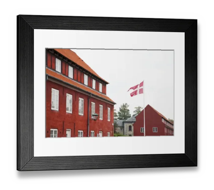 Framed Print : Copenhagen, Denmark - A Danish flag is flying in front of red military barracks Framed Print : Copenhagen, Denmark - A Danish flag is flying in front of red military barracks