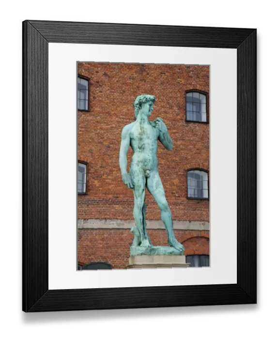 Framed Print : Copenhagen, Denmark - Low angle view of a sculpture of David. A brick building is