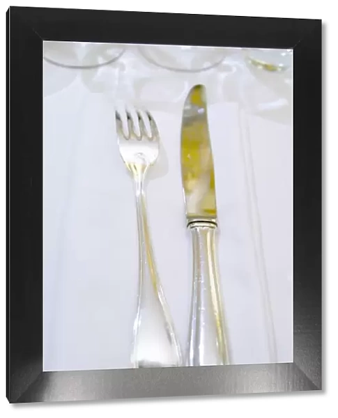 Knife and fork on a white linen napkin and table cloth in the restaurant Le Gourmandin
