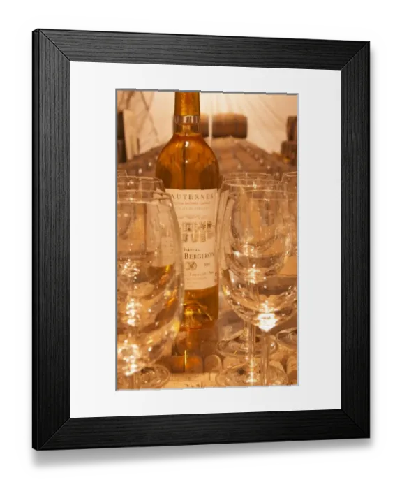 Framed Print : Wine tasting in the cellar, glasses, a bottle and barrels in the background - Chateau Haut Bergeron