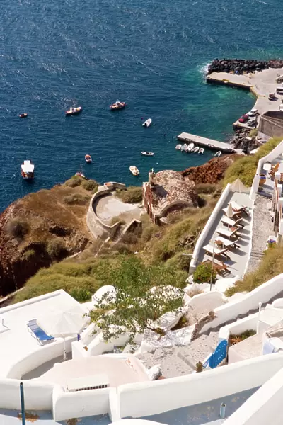 Along the cliff of Oia, view the boats docked in the water, Greece