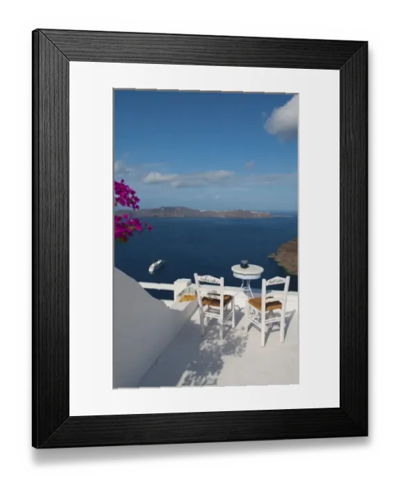 Framed Print : Postcard scene of two lonely chairs on terrace with table ready for tourists in Santorini Framed Print : Postcard scene of two lonely chairs on terrace with table ready for tourists in Santorini