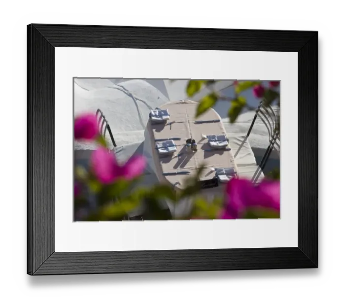 Framed Print : Greece, Santorini, Thira, Oia. Looking through bougainvillea to a patio table set for dinner