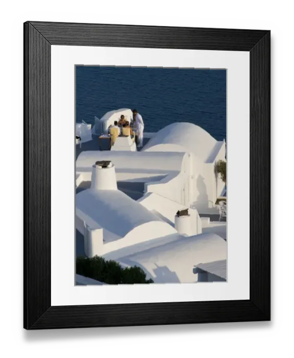 Framed Print : Greece, Santorini, Thira, Oia. Two couples are served for dinner at white villa overlooking sea