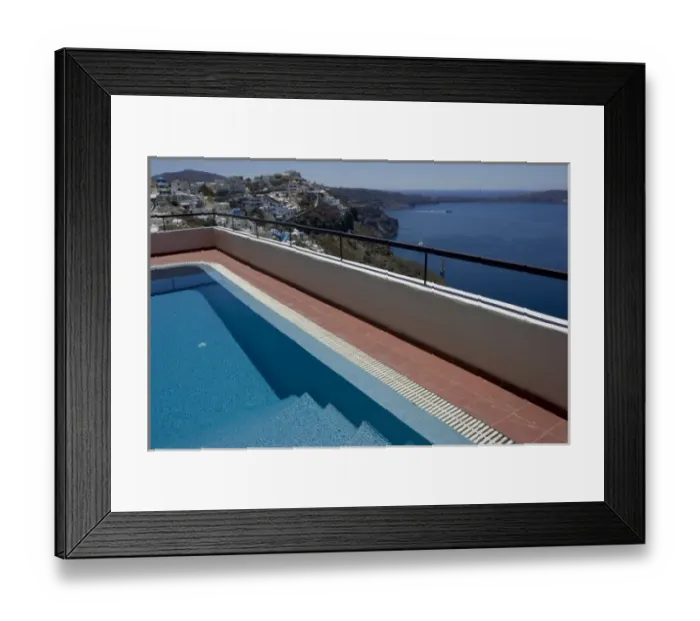 Framed Print : Greece, Santorini. Swimming pool overlooking town of Firostefani and yachts on the Aegean Sea