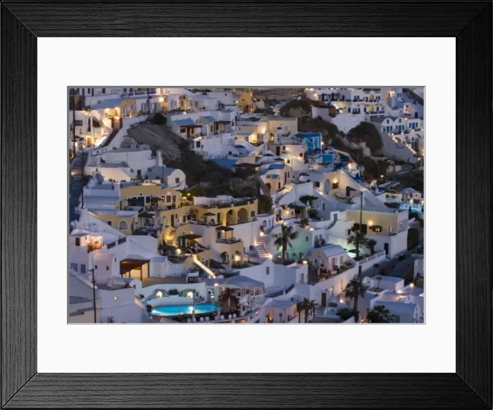 Framed Print : Greece, Santorini, Firostefani. Close-up of cliffside villas with lights coming on at nightfall