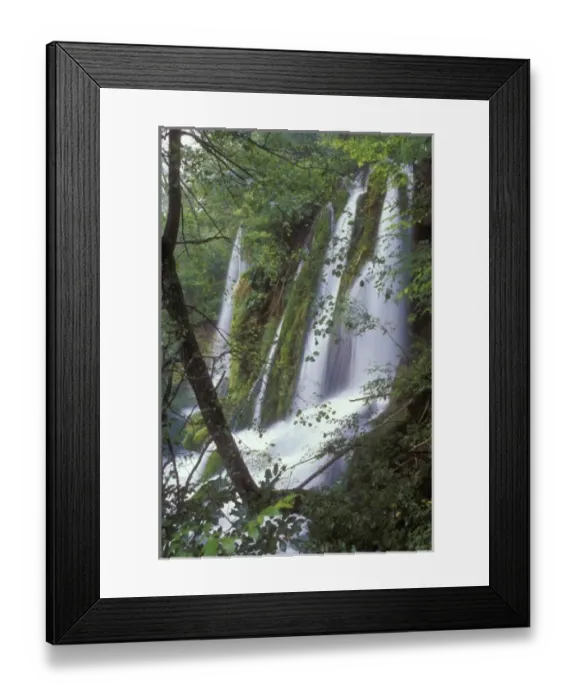 Framed Print : Several streams of water tumble down the edge of a small cliff amidst lush vegetation Framed Print : Several streams of water tumble down the edge of a small cliff amidst lush vegetation