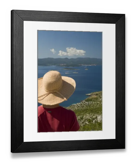 Framed Print : Croatia, Dalmatia, Female tourist in straw hat gazes at lush fields and town of Orebic