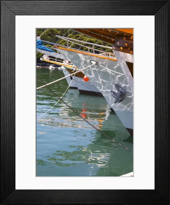 Framed Print : The bow of several yachts boats ships, white, wood, with reflections in the water