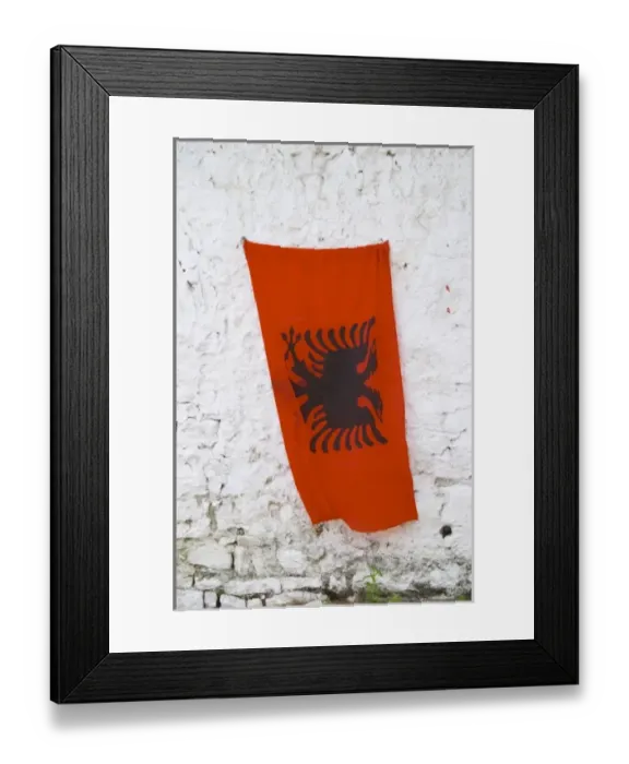 Framed Print : The Albanian flag, red with black double headed eagle, against a white washed stone wall Framed Print : The Albanian flag, red with black double headed eagle, against a white washed stone wall