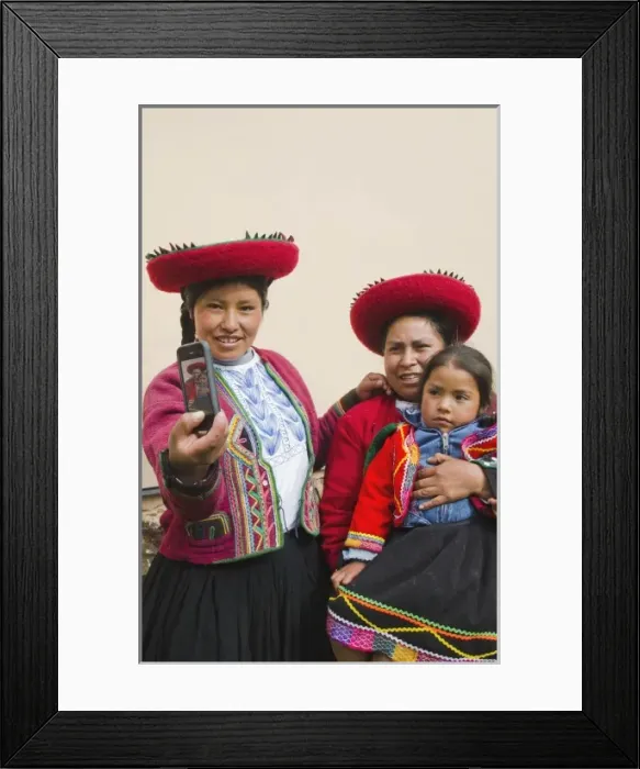 Framed Print : Modern life in Peru family in traditional dress and hat taking photo with cell phone communicating