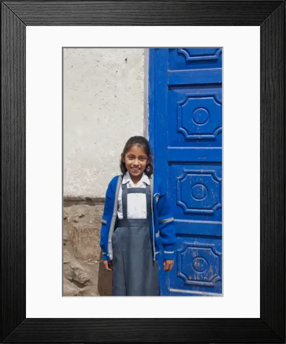 Framed Print : School child aged 10 in uniform and blue door in small town of Pisaq Peru (MR)