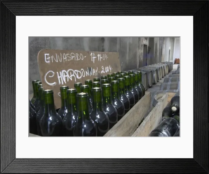 Framed Print : Bottles of Chardonnay 2004 standing in wooden crates. Bodega Plaza Vidiella Winery