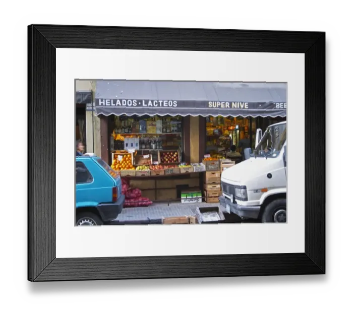 Framed Print : A grocery store with froits and vegetables displayed on the pavement. Cars parked in front Framed Print : A grocery store with froits and vegetables displayed on the pavement. Cars parked in front